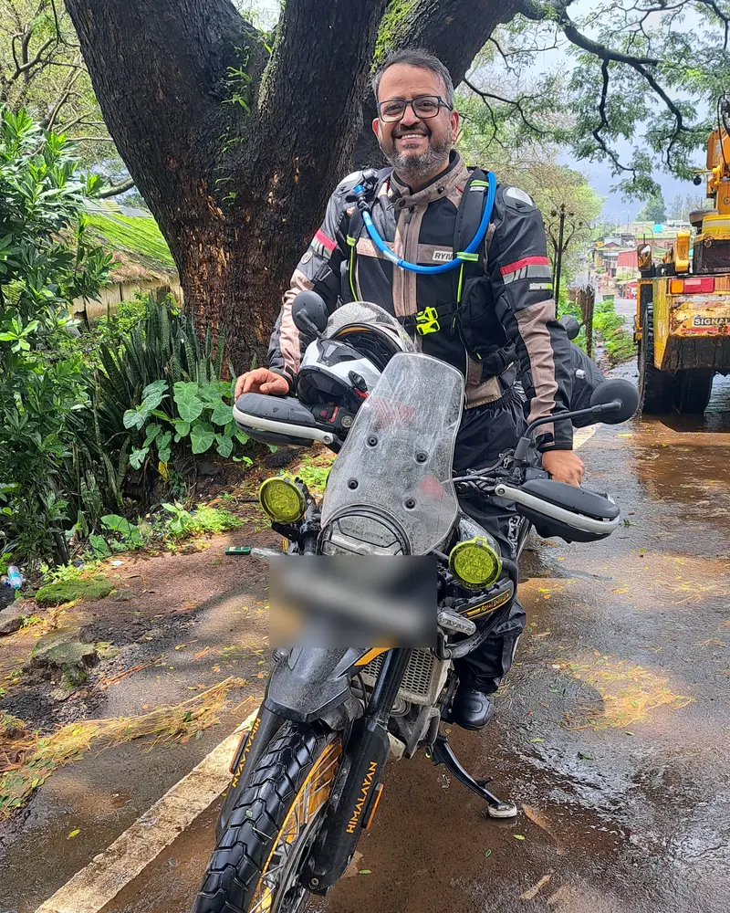 Abhishek in riding gear on his Royal Enfield Himalayan 450 on a wet monsoon road