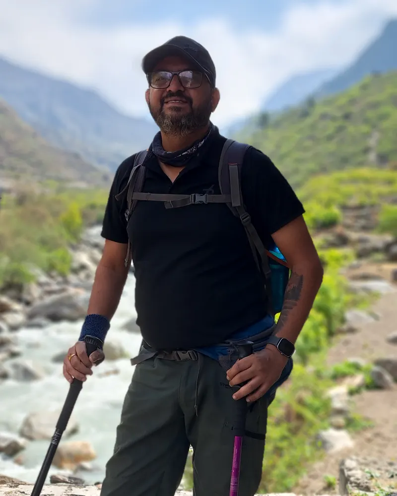 Abhishek with trekking poles beside a Himalayan river valley